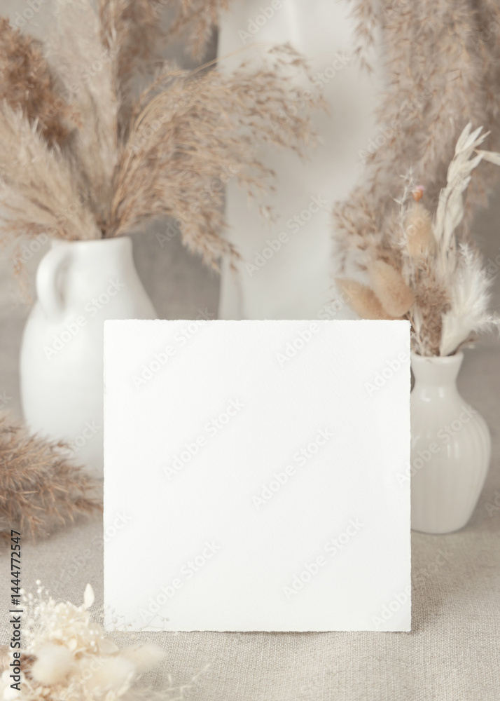 Blank card near dry beige pampas grass on linen closeup, mockup. Bohemian wedding stationery
