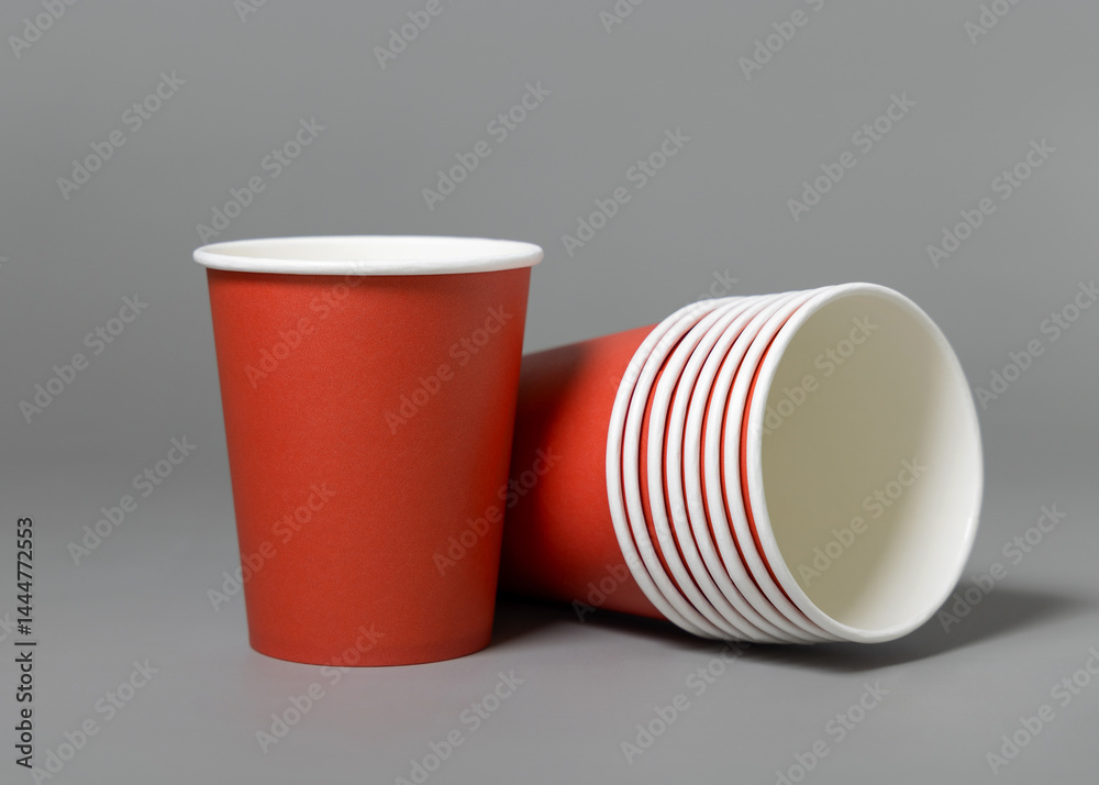 Disposable red paper cups on a gray closeup, mockup. No plastic and sustainable Christmas