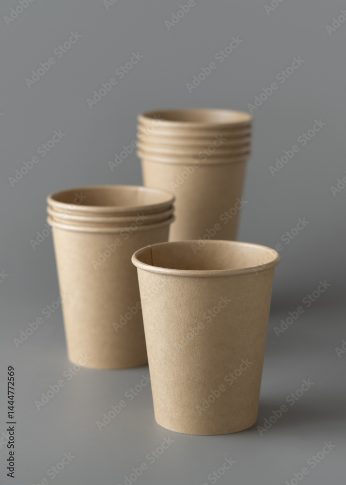 Disposable beige kraft paper cups on a gray closeup, mockup. No plastic and sustainable lifestyle
