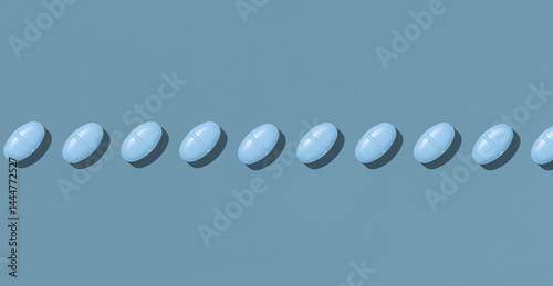 Obraz na płótnie Blue medical pills in a line on blue top view, hard light. Pharmaceutical products for healthcare w salonie