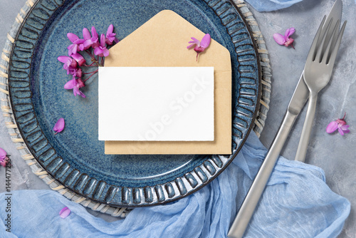Obraz na płótnie Wedding table place with a card over envelope near fabric and purple flowers top view, mockup w salonie