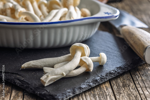 Raw white shimeji mushrooms on cutting board.