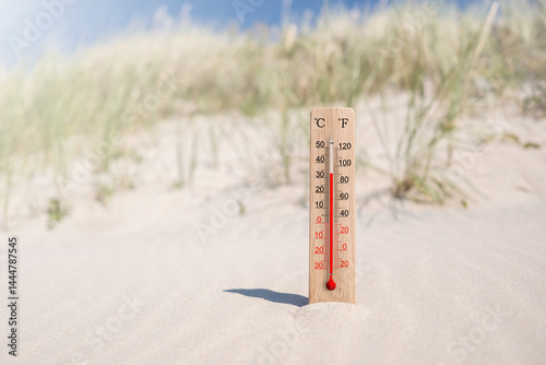 Wooden celsius and fahrenheit scale thermometer in the sand. Ambient temperature plus 33 degrees. Hot summer day