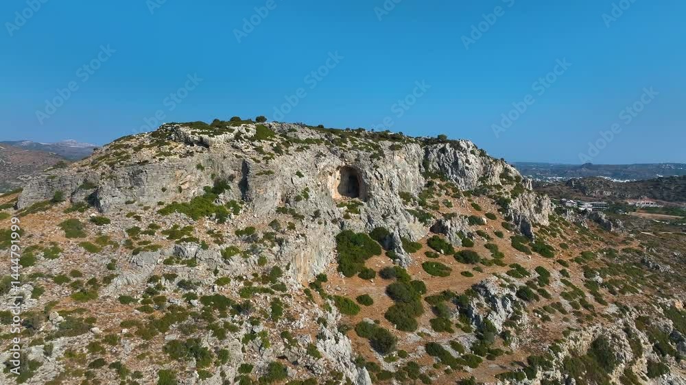 Aerial pull back away from a mountain cave, sunny morning in Rhodes, Greece