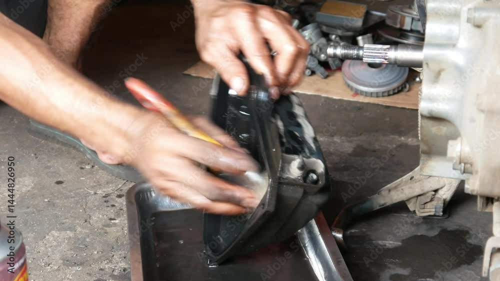 A mechanic performs repairs, maintenance and cleaning on the CVT components of a motorbike A mechanic performs repairs, maintenance and cleaning on the CVT components of a motorbike