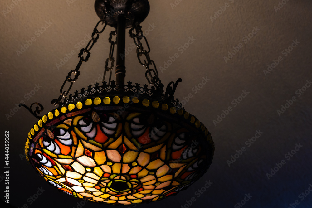 Colorful stained glass chandelier with intricate patterns, casting warm light