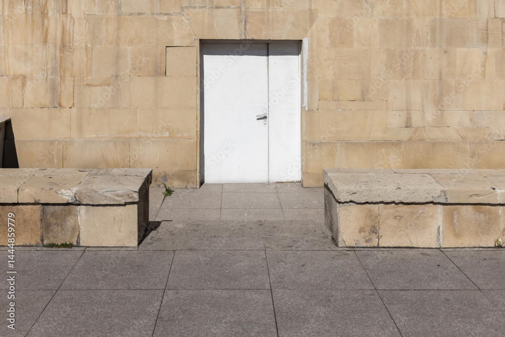 A simple white door set into a textured stone wall, background photo
