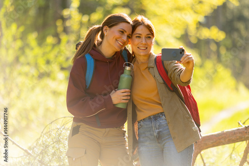 Obraz na płótnie Friends capture a joyful moment during a spring hike in the vibrant green forest filled with sunlight and adventure w salonie