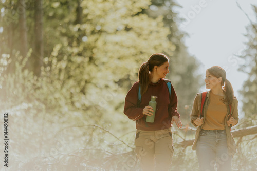 Obraz na płótnie Two friends enjoy a cheerful hike through a sunlit forest during a vibrant spring afternoon w salonie