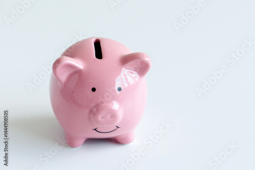 Ceramic pink piggy bank sits on a white surface, symbolizing saving and financial planning for individuals