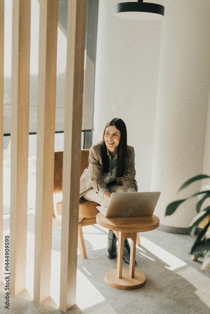 Businesswoman working diligently on laptop in stylish modern office during bright daytime