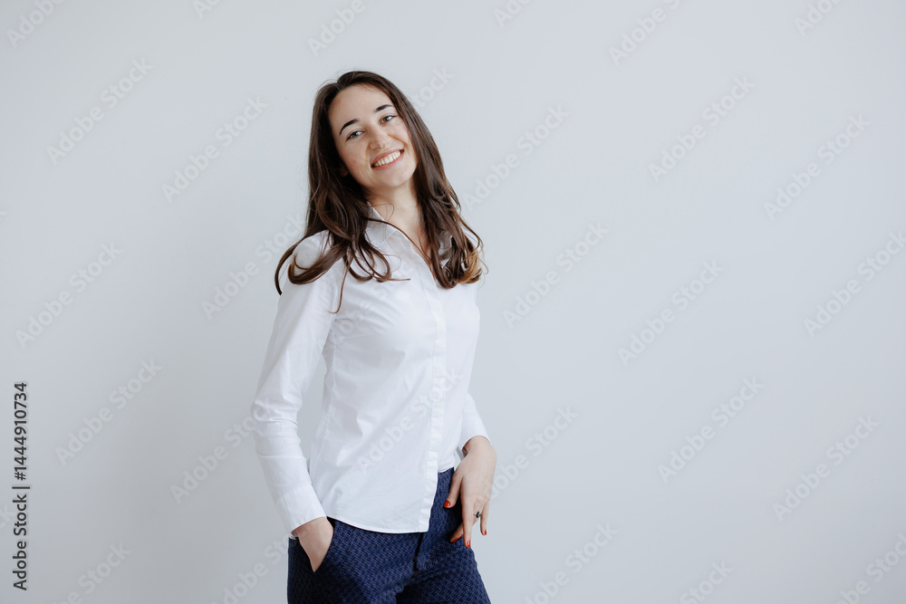 Smiling woman in white shirt poses against simple background in indoor setting with neutral colors