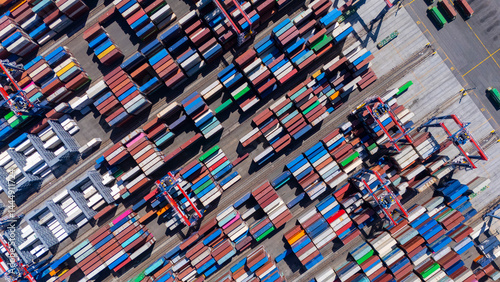 Aerial top view of organized stacks of colorful shipping containers at a busy cargo yard. The image reflects the logistics efficiency and volume of global trade through maritime transport.