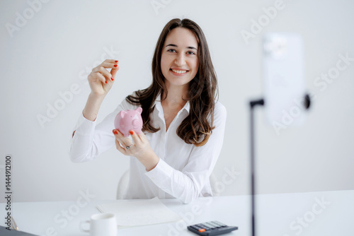 Woman presenting personal finance tips while holding a piggy bank in a modern workspace