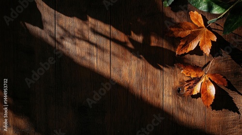 Close-up of a wooden surface with two autumn leaves on it. the leaves are orange and yellow in color and appear to be dried and wilted. the wooden surface is dark and has a rough texture. photo