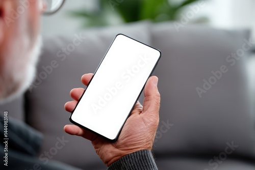 Senior man holds phone, blank screen.