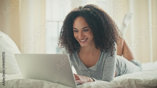 Wallpaper Mural Relaxed African American female lying on stomach on bed using laptop with one hand resting under chin. Watching content or reading articles while wearing cozy loungewear and white socks. Torontodigital.ca