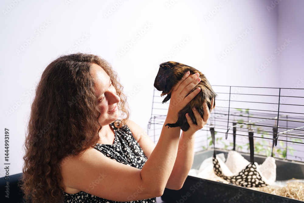 Woman interacts with pet guinea pig in a cozy indoor setting during the afternoon