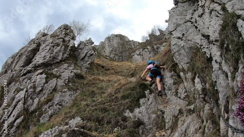 A single steel ladder anchors a precarious drop, where climber ascends cautiously on the steep Giumenta via ferrata above Lecco.