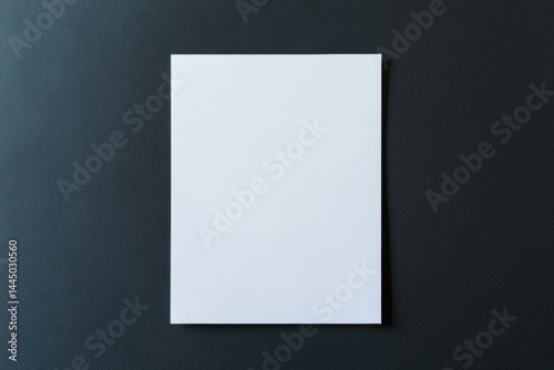 Blank white sheet of paper placed on a dark textured background. Minimalist composition for mockup design, branding, corporate identity, or stationery presentation with clean space for text or logo.