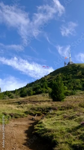Colorful Paragliders Fly Above Grassy Slopes of Puy de Dome Volcano