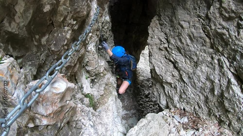 Sunlight filters into a rugged grotto as a climber pauses to clip in on Resegone’s daring Caminetto via ferrata route near Lecco.