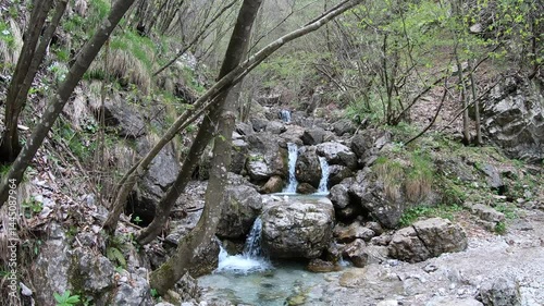 Beside a babbling brook, a lone trekker pauses to drink in the gentle melody of water over smooth stones toward Erve town.