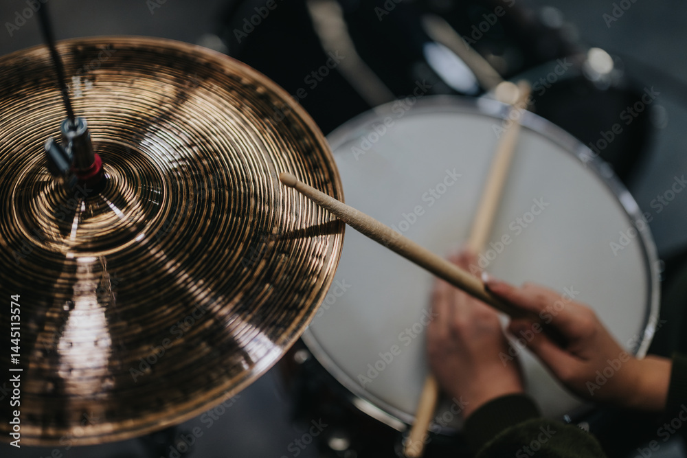 Obraz premium Hands holding drumsticks playing a drum kit and cymbals, illustrating musical creativity in a studio environment.
