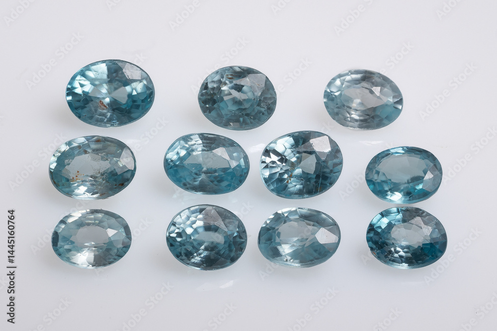 A stunning array of eleven round-cut, light blue aquamarine zircon gemstones displayed against a clean white background, exhibiting varying shades and clarity