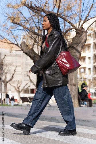 Young woman walking on crosswalk in urban setting