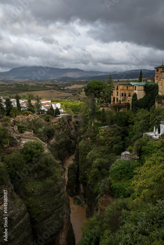 View of the village of Ronda, Spain, either side of its famously deep gorge, looking towards the rolling hills of Andulasia. It is a rare cloudy day in southern Spain photo