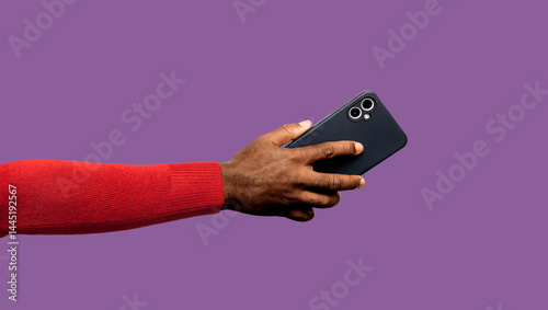 Outstretched Black African hand in red long sleeves body con sweater holding mobile phone isolated on purple background. Lift raise showing back facing view