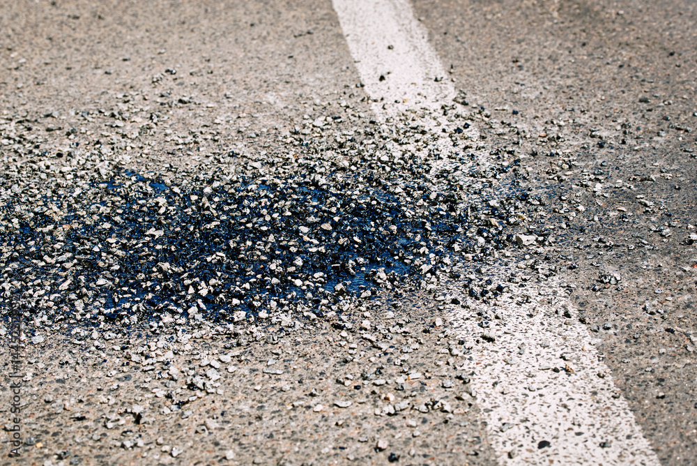 Close view of road construction maintenance using gravel, bitumen, and resin to repair cracked asphalt surface with fresh patch sealing urban pavement damage. Street maintenance process with patchwork