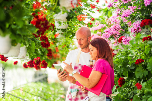 Wallpaper Mural Florists using digital tablet discussing inventory in greenhouse full of flowers Torontodigital.ca