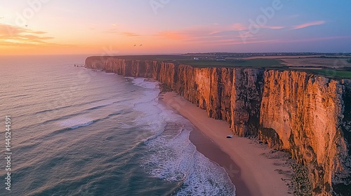 Coastal cliffs meet ocean at sunset