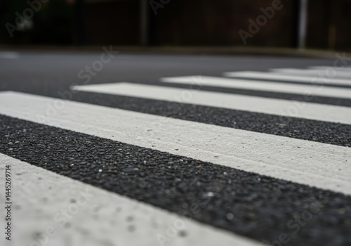 Obraz na płótnie Close up view of pedestrian crosswalk lines on dark asphalt road surface after rain. Road safety markings and urban infrastructure element. w salonie