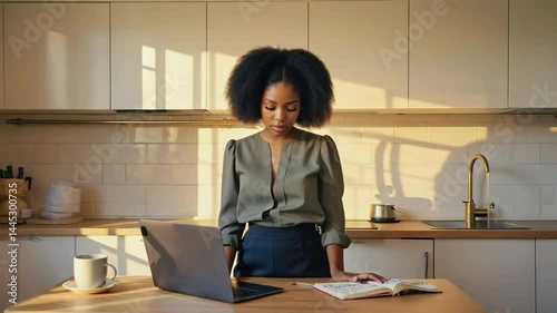 Young businesswoman in kitchen uses laptop for professional communication