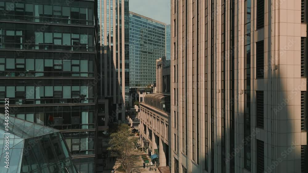 Upward aerial movement beside a tall modern building, revealing danse urban architecture in a Chinese city.