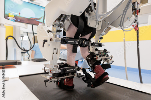 Child using robotic gait trainer for walking therapy on a treadmill at pediatric rehabilitation clinic photo