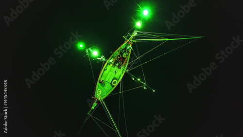 Obraz na płótnie Low angle night view of a squid fishing boat using green lights to attract its prey, creating a surreal atmosphere in the darkness off the coast of Koh Phangan, Thailand w salonie