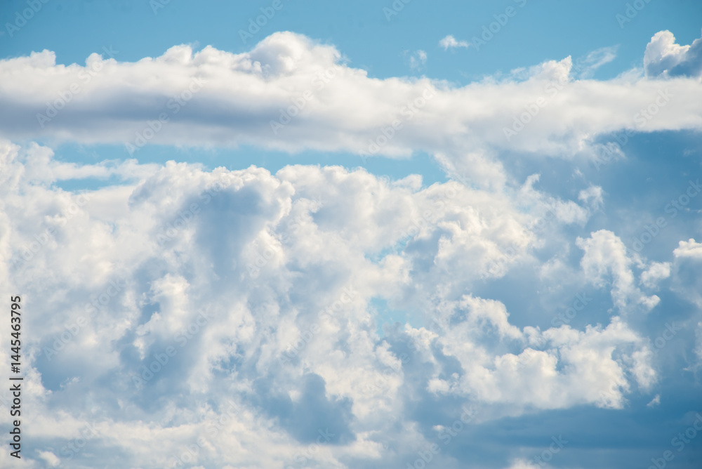A cluster of cumulus thunderclouds in a bright blue sky during the daytime. Weather forecast. Thunderstorm formation. meteorology A cluster of cumulus thunderclouds in a bright blue sky during the daytime. Weather forecast. Thunderstorm formation. meteorology