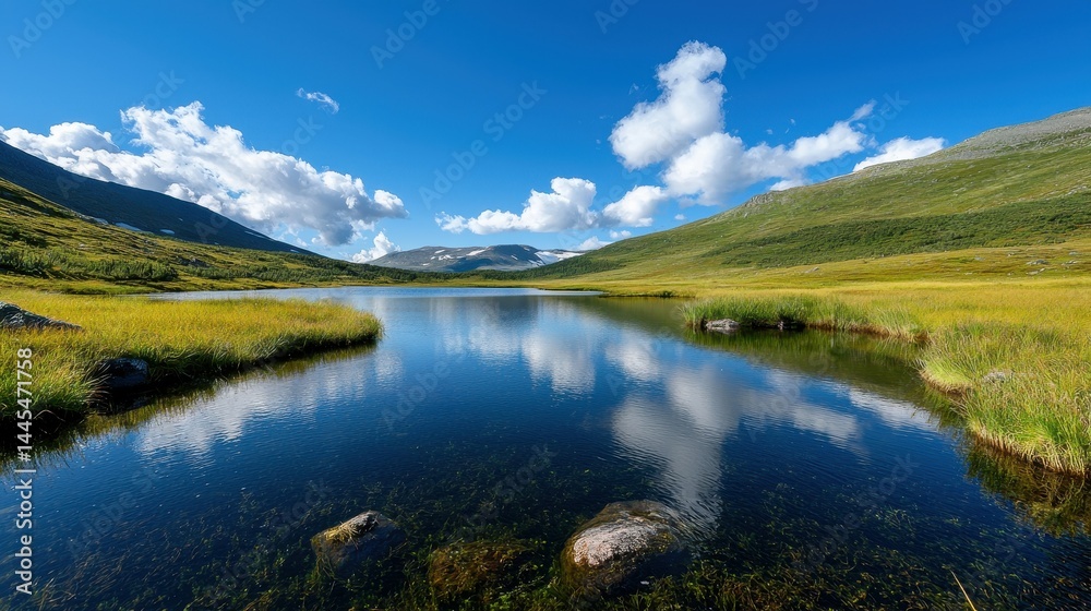 Fototapeta premium Scenic view of tranquil lake surrounded by lush green hills and vibrant blue sky.