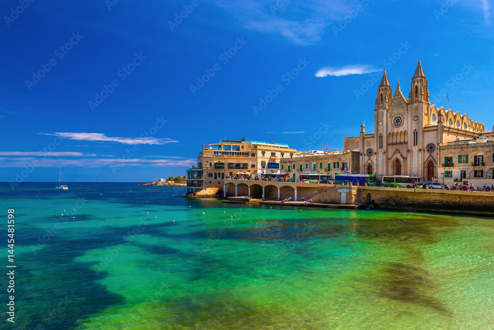 Picturesque view of the Knisja tal-Karmnu and turquise-green water in St. Julian's Bay in Sliema, Malta