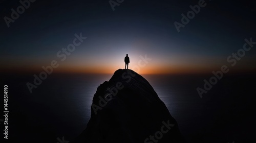 Silhouette of a person standing atop a mountain peak at dawn, overlooking the vast ocean