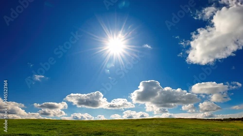 Bright Sun Over Field with Soft Clouds Beneath Clear Blue Sky