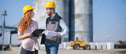 Engineers in front of silo talking and making plans