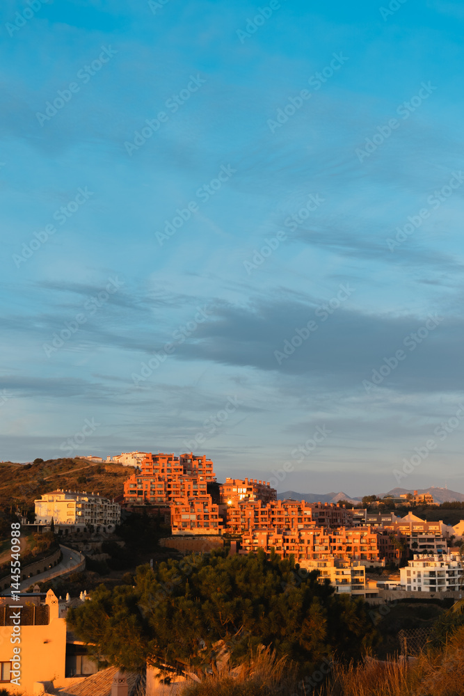 Obraz premium Hillside residential area at sunset with orange tones on buildings in Calahonda, Costa del Sol, Spain