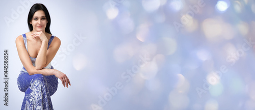 Obraz na płótnie Banner with studio portrait of young beautiful smiling woman with black loose hair against light blue background. w salonie