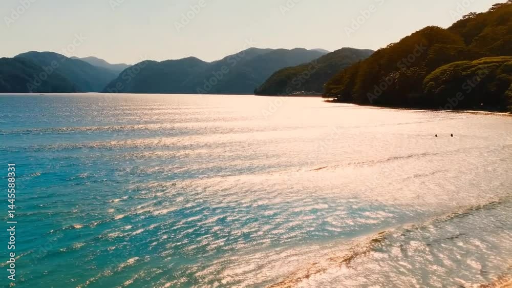 Serene beach view with lush green mountains and sparkling waters during golden hour