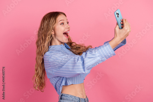 Obraz na płótnie Young female student in stylish casual style taking a joyful selfie, showcasing a cheerful mood on a vibrant pink background w salonie